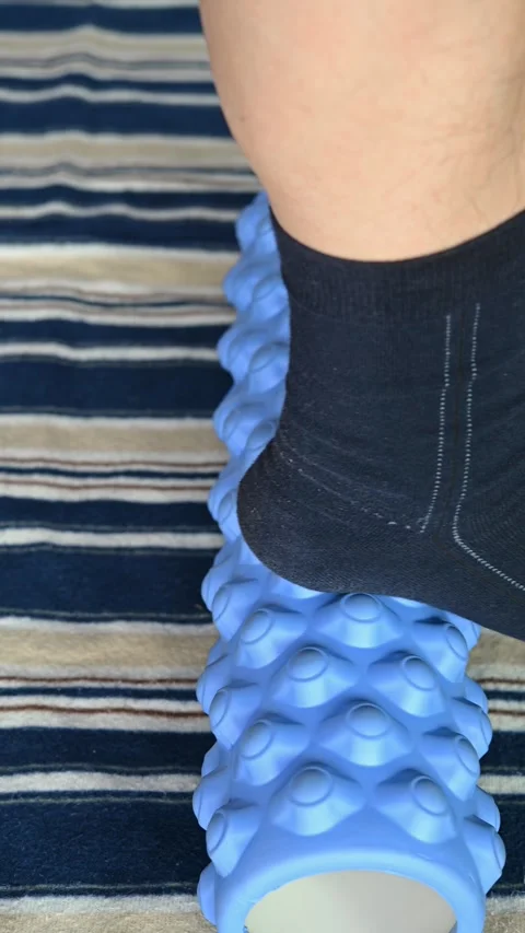 Man stepping on a  foam roller  to relax his muscles at vertical composition Stock Footage 260701357
