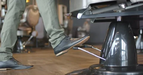 Man stepping from left, repeatedly pressing salon chair pedal, adjusting height, Stock Footage 339232181