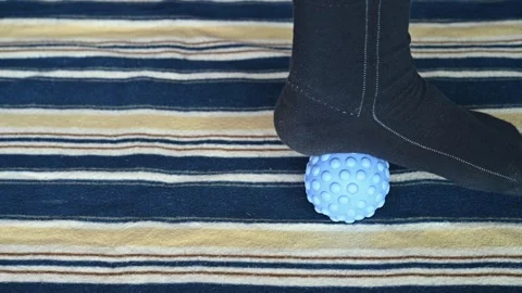Man stepping on a peanut-shaped massage ball to relax his muscles Stock Footage 260532729
