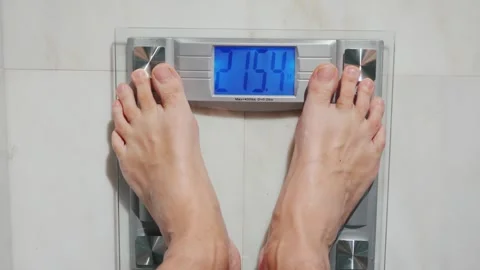 Man steps onto bathroom scale showing weight 215.4 lbs or 97.7 kg motion fo.. Vídeos de archivo 334859160