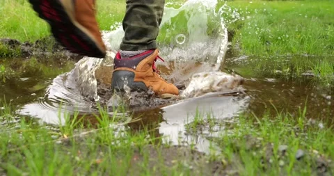 Man steps into a muddy puddle and that step makes mud splashing Stock Footage 196827560