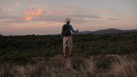 The man with a stick and hat walking on the mountain. Sunset. Slow motion. Stock Footage