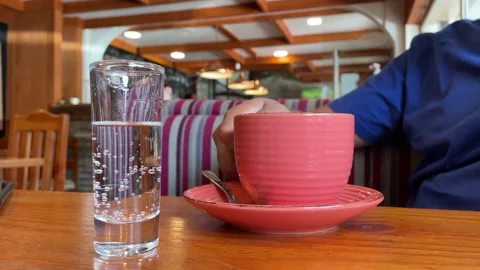 Man stirring a coffee and taking the first sip in a rustic coffee house Stock Footage 170888392