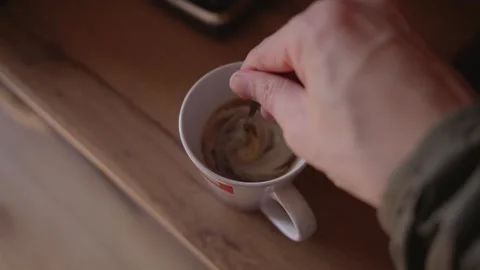 Man Stirring Coffee with Teaspoon in White Cup, Top View Kitchen Scene Stock Footage 329889428