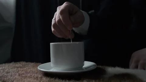 Man stirring a cup of coffee standing on the table 库存影片 168816191