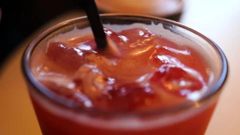 Man stirring a red drink with ice in a glass with a straw Video stock 138895743
