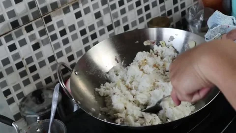 A man is stirring rice in a wok to cook fried rice. Stock Footage 242569705