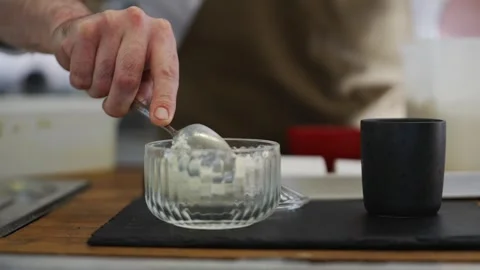 A man is stirring a white container with a spoon Stock Footage 301630425