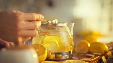 A man stirs a revitalizing tea blend in a teapot combining sliced lemons and Stock Footage 331309523