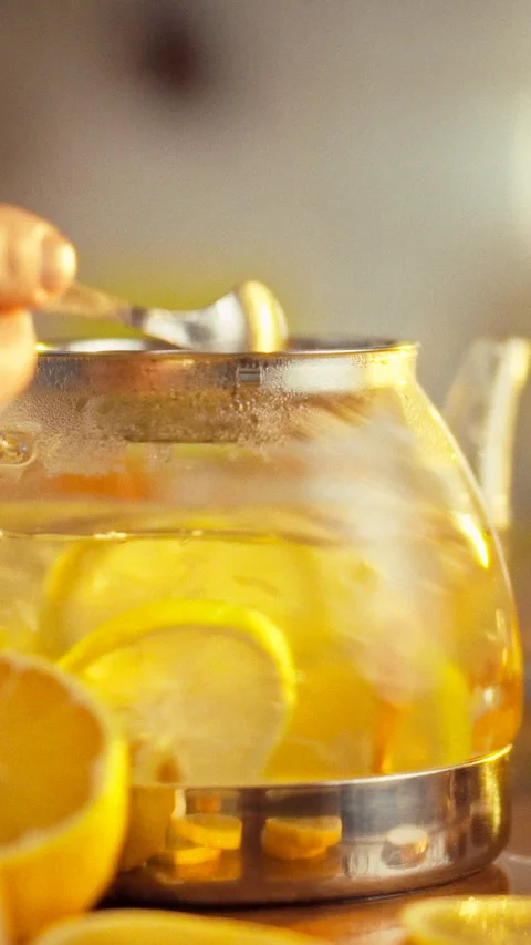 A man stirs a tea blend in a teapot adding sliced lemon and ginger creating Stock Footage 342719397