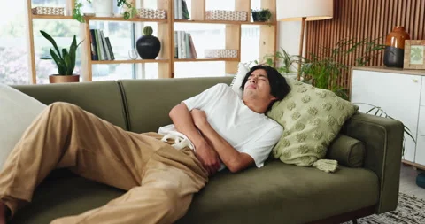 Man, stomach ache and sofa with constipation for diarrhea or gastrointestinal Stock Footage 327372163
