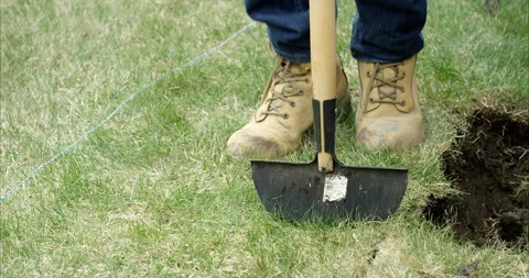 Man stomps on lawn edger to break up sod grass - close up on feet - slow moti Stock Footage 132361578