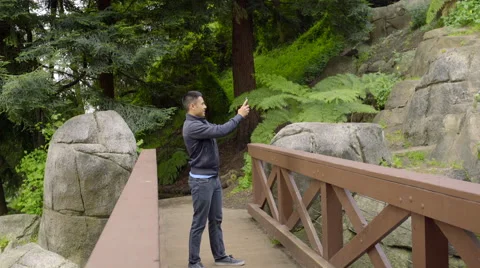 Man Stops On A Bridge And Takes A Photo Of A Waterfall (4K) Video stock 51207755