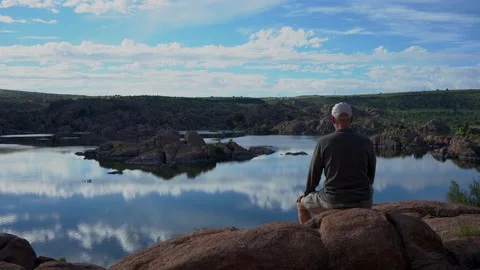 A man stops at a highpoint to take in the view at a scenic lake Stock Footage 282664389