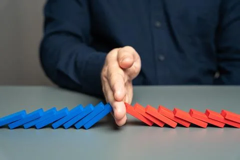 A man stops two domino chains from colliding. The concept of stopping a confl Stock Photos