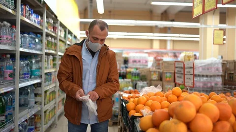 A man in a store chooses oranges. Masked man. A man wears medical gloves Stock Footage 129353673