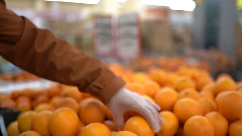 A man in a store chooses oranges. Masked man. A man wears medical gloves Stock Footage 129354495