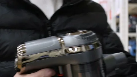 A man in a store chooses a vacuum cleaner, tries to connect the pipe. Buying a Stock Footage 201687864