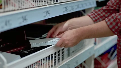 A man in a store selects a checkered notebook and examines it. Stock Footage 131439347