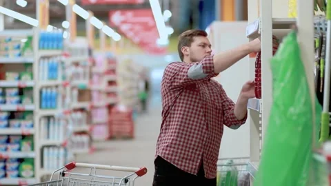 A man in a store selects a container of liquid in his cart. Stock Footage 131182143