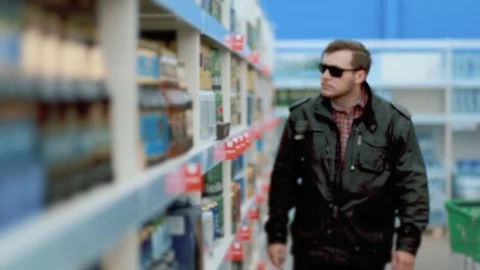 A man in a store steals a can of beer in a store. 스톡 동영상 129059816