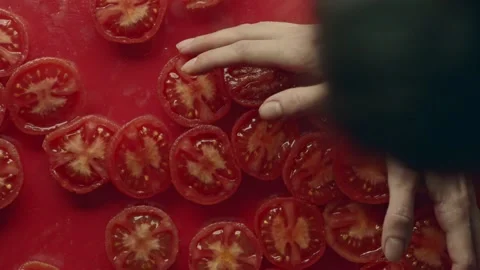 A man straightening split tomatoes on a red background. Stock Footage 170012023