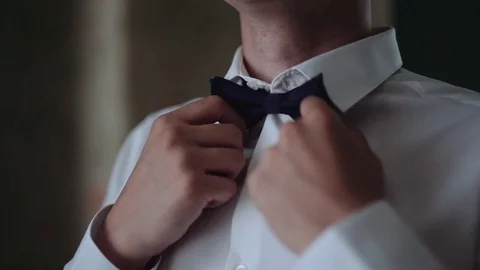 Man straightens bow-tie. Young man puts and adjusts classic black bow tie Vídeos de archivo 80953576
