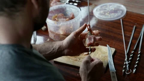 A man strands pieces of raw meat on a skewer. over-the-shoulder view Stock Footage 163661783