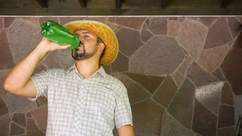 A man in a straw hat drinks from a green bottle 4K Video stock 115552429