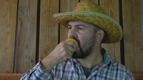 A man in a straw hat eats an Apple 4K Stock Footage 95925036