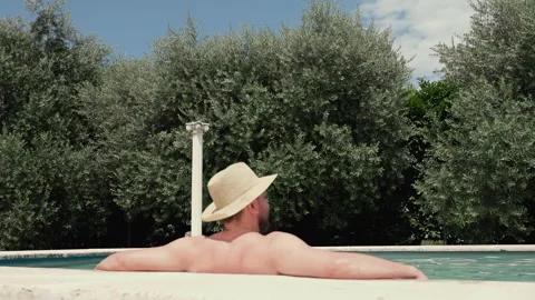 Man in straw hat leaning on marble poolside and enjoying nature Stock Footage 288452571