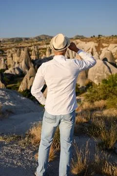 Man in straw hat looking at Cappadocia valley panoramic volcanic rock landscape, Фото