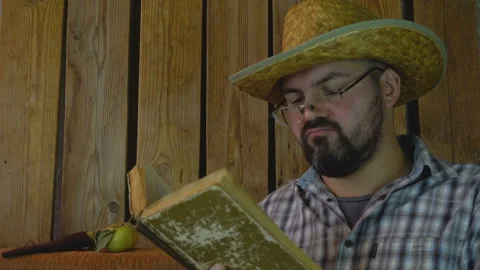 A man in a straw hat looking at an old book 4K Vídeo Stock 95922768