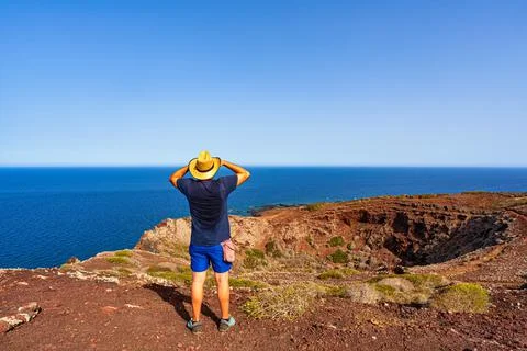 A man with a straw hat looking the sea from the top of the volcano called Mon Photos