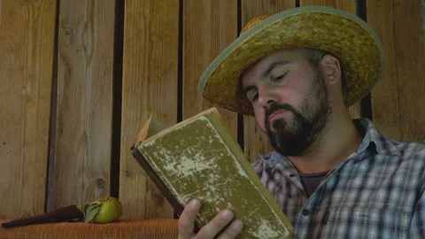 A man in a straw hat reading an old book 4K Video stock 95925543