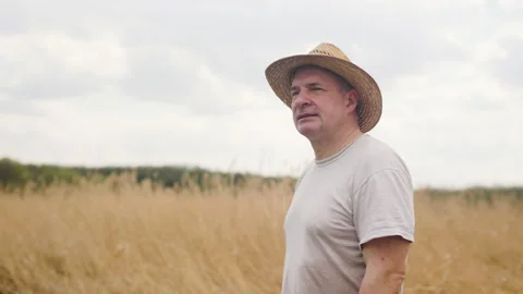 A man in a straw hat walks through a field of straw and looks around Video stock 191153673