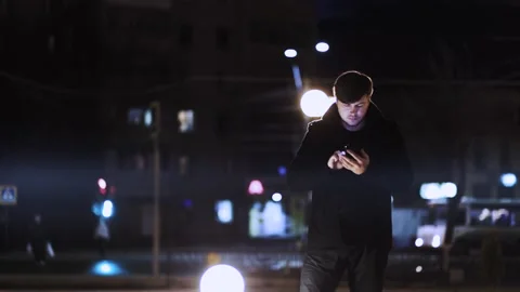 A man on the street at night, using a smartphone, communicates on the Internet Stock Footage 152983712
