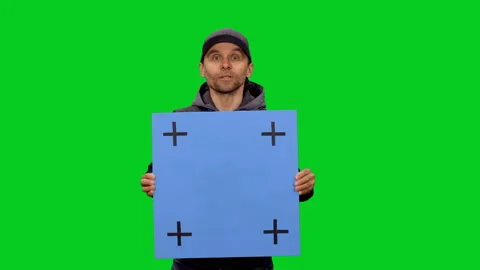 Man in streetwear talking while standing with blank placard on green screen Stock Footage 130794487