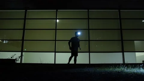 A man stretches his body before going for a night run with his headlamp Stock Footage 210225699