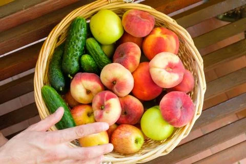 The man stretches his hand for fruit in a basket. Stock Photos