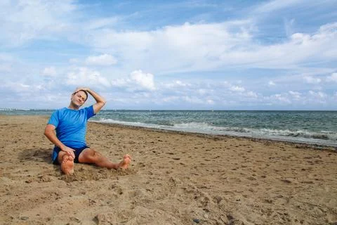 Man Stretching on a Beach Under Blue Sky Stock Photos