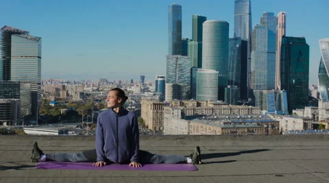 Man stretching on the roof against the backdrop of the city Video stock 68762753