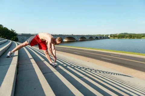 Man stretching on the steps during an intense workout Stock Photos