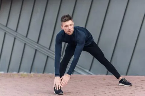 Man stretching while jogging on a running track. Stock Photos