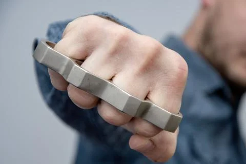 A man strikes a brass knuckles on a light background, a street gang of hooligans Stockfoto's