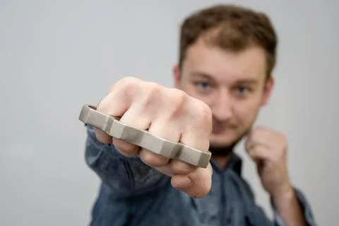 Man strikes brass knuckles on a light background, a prohibited weapon in a fight Stock-Fotos