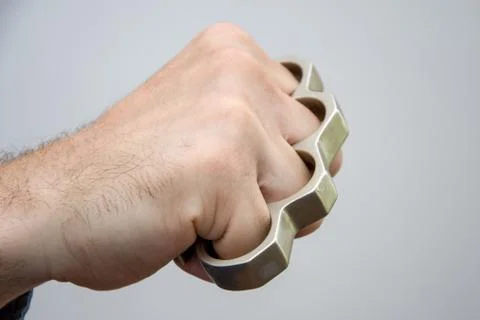 Man strikes brass knuckles on a light background, a prohibited weapon in a fight Stock Photos