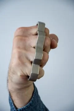 Man strikes brass knuckles on a light background, a prohibited weapon in a fight 写真素材