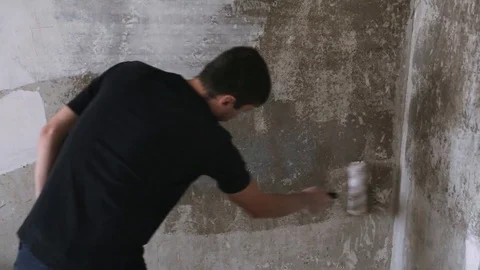 Man strikes the primer on the plaster wall Stock Footage 83872920