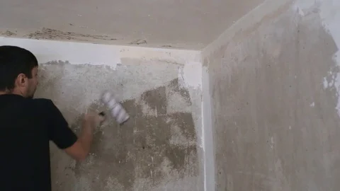 Man strikes the primer on the plaster wall Stock Footage 83872996